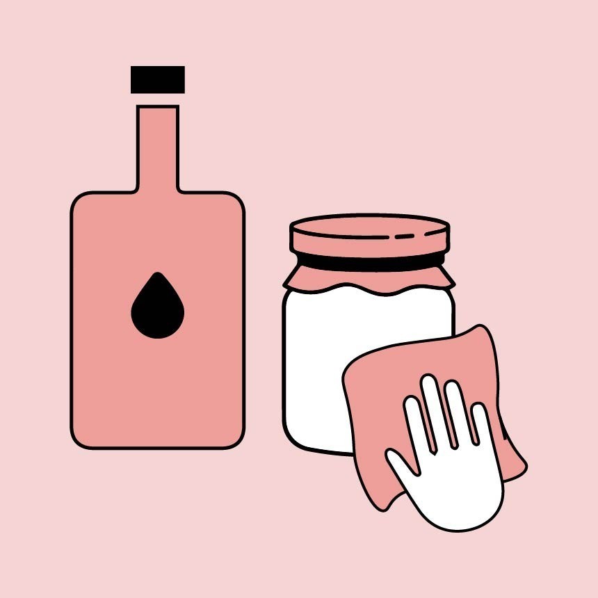  Ένα χέρι σκουπίζει ένα λευκό βάζο με ένα ροζ πανί, προετοιμάζοντας την επιφάνεια. Δίπλα στέκεται ένα μπουκάλι με υγρό καθαρισμού.