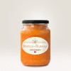Η εικόνα δείχνει ένα βαζάκι Kürbis-Chutney με μια διακοσμητική ετικέτα. Το τσάτνεϊ έχει ένα ζωηρό πορτοκαλί χρώμα και το βαζάκι έχει μαύρο καπάκι. Η ετικέτα περιέχει το κείμενο 'Kürbis-Chutney für Gourmets' σε ένα ανοιχτόχρωμο φόντο.