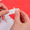 Ένα άτομο τραβάει ένα κομμάτι ταινίας από ένα ρολό, με ένα κόκκινο ανάγλυφο φόντο.
